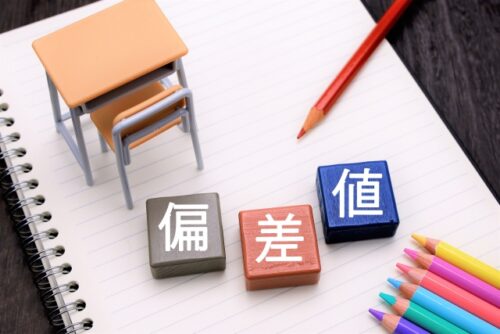 学校の机やノート、鉛筆が描かれており、「偏差値」の文字が表示されている